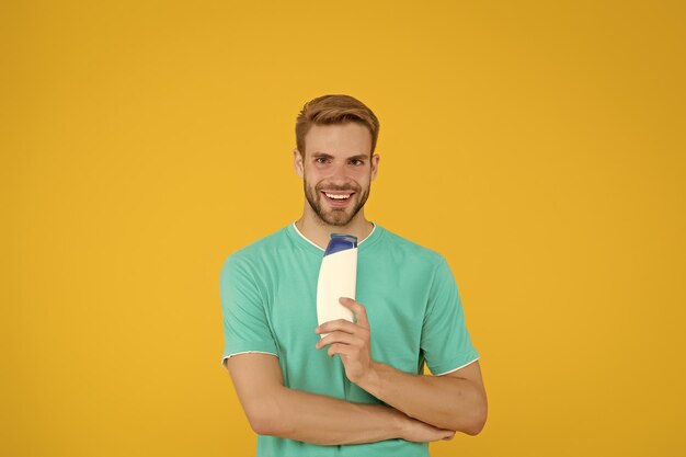 Homem bonito segurando garrafa de shampoo Cuidados com o cabelo Saúde e cuidados com a saúde Cosméticos masculinos Barbeiro profissional Cosméticos de cuidados com o corpo para banho ou chuveiro Homem barbudo segurando tubo de gel Barbearia