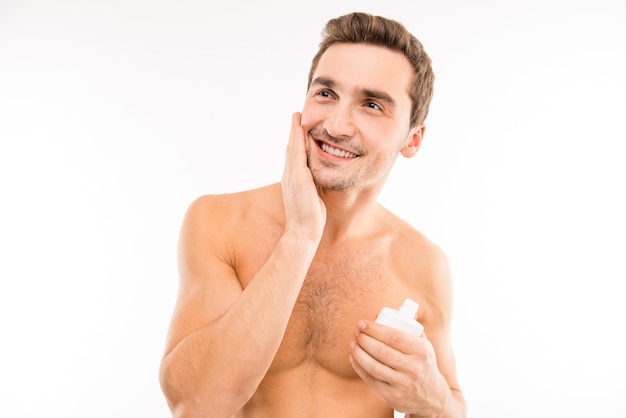 Homem bonito segurando loção após a barba, borrando a bochecha