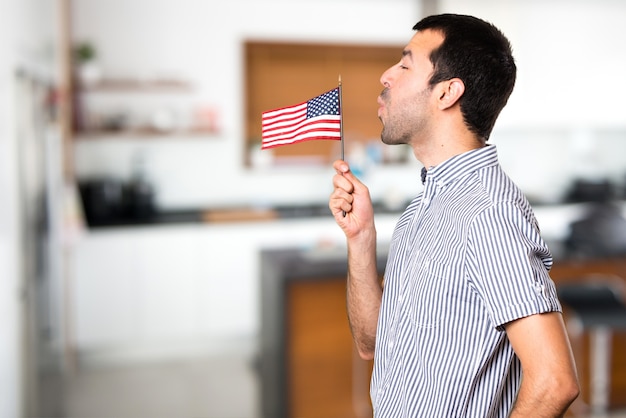 Homem bonito segurando uma bandeira americana dentro da casa