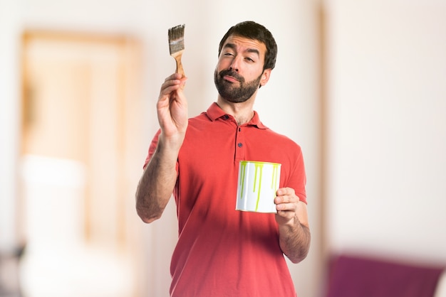 Homem bonito segurando uma panela de tinta em fundo não focado