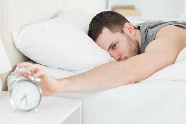 Homem bonito sendo despertado por um despertador