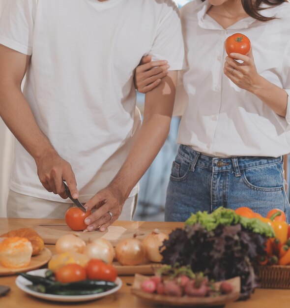 Homem bonito sentado perto de sua esposa na cozinha Casal da família vê mídia social navegar na web enquanto está sentado na mesa da cozinha com laptop genérico Casal trabalhando com laptop em casa