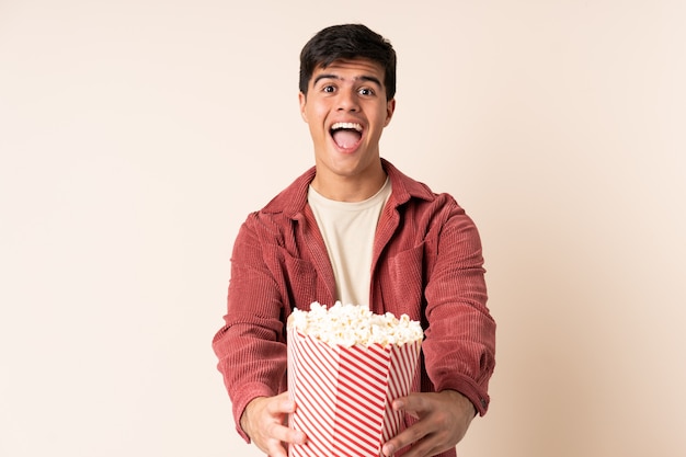 Homem bonito sobre fundo isolado, segurando um grande balde de pipocas