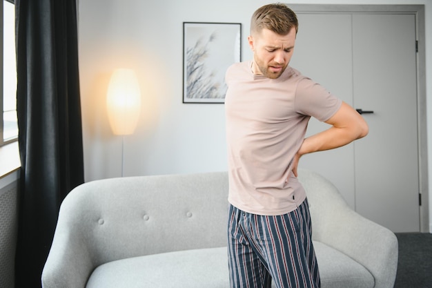 Homem bonito, sofrendo de dor nas costas em casa