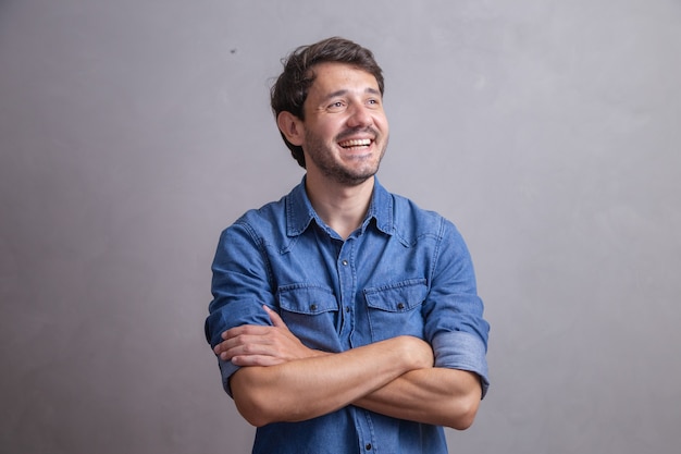 Foto homem bonito sorridente em pé com os braços cruzados, isolado em um fundo cinza