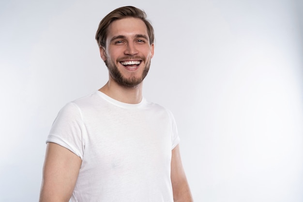 Homem bonito sorridente sexy em t-shirt branca isolado no branco.