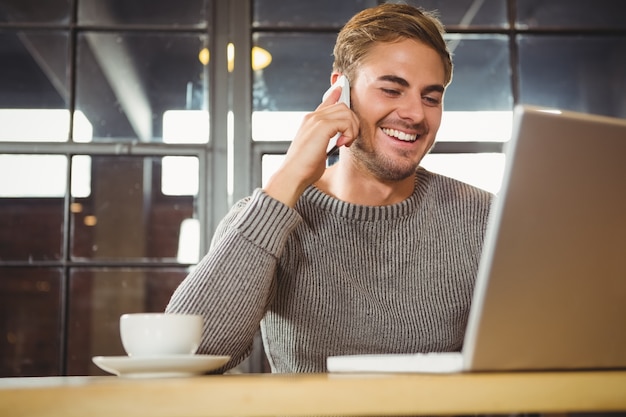 Homem bonito sorrindo e telefonando com smartphone