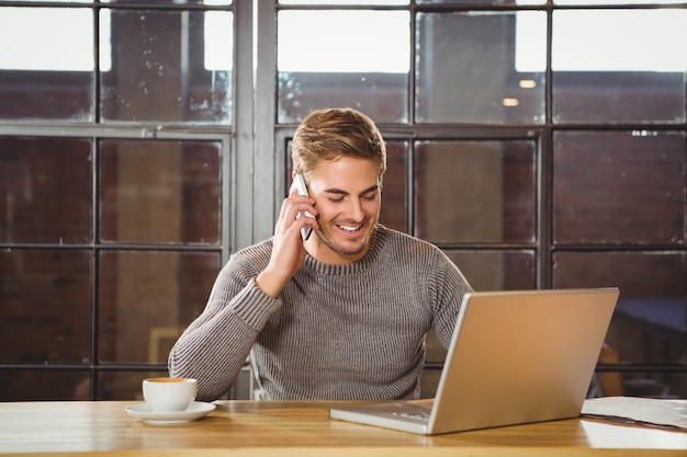 Homem bonito sorrindo e telefonando com smartphone