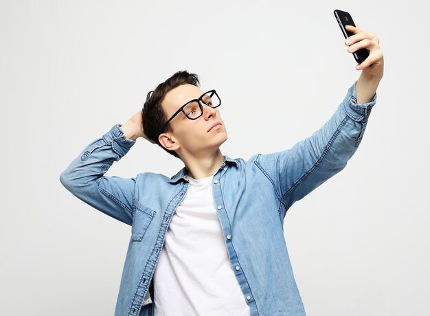 Homem bonito sorrindo na câmera tomando selfie isolado sobre fundo branco