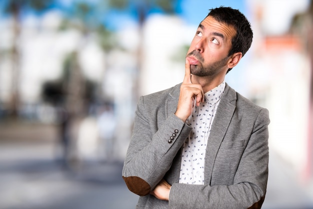 Homem bonito tendo dúvidas sobre o fundo não focado