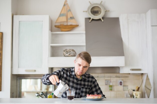 Homem bonito tomando café na cozinha