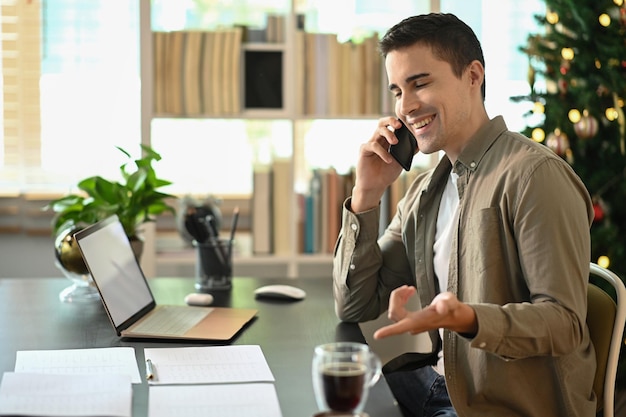 Homem bonito, trabalhando com computador portátil e falando no celular