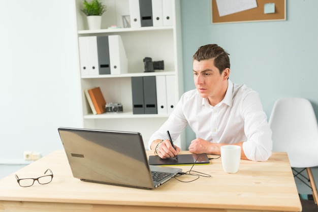 Homem bonito trabalhando com tablet gráfico