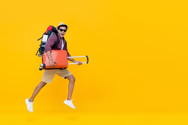 Homem bonito turista indiano com mochila segurando a bagagem e pulando