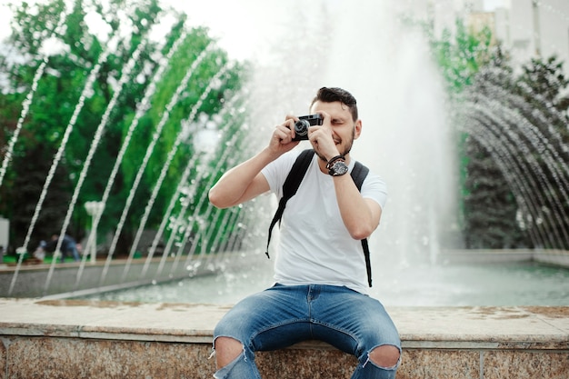Homem bonito turista tirando fotos com câmera retro no parque