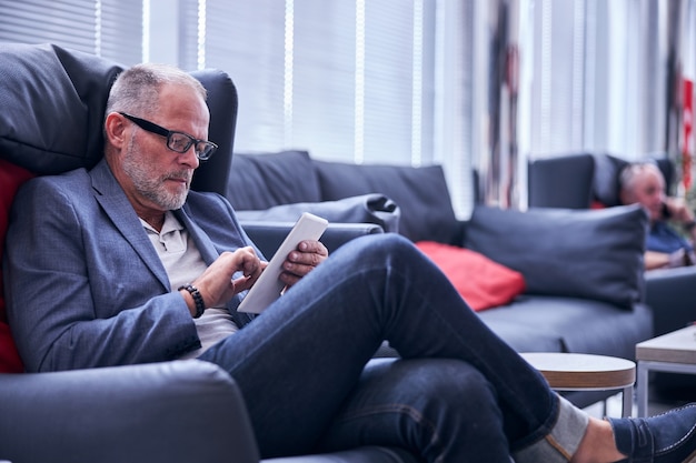 Homem bonito usando computador tablet no centro de negócios