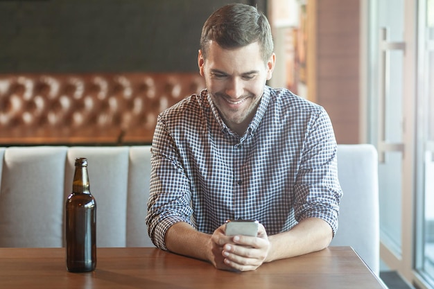 Homem bonito usando smartphone no café