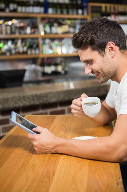 Homem bonito usando tablet e tomando café