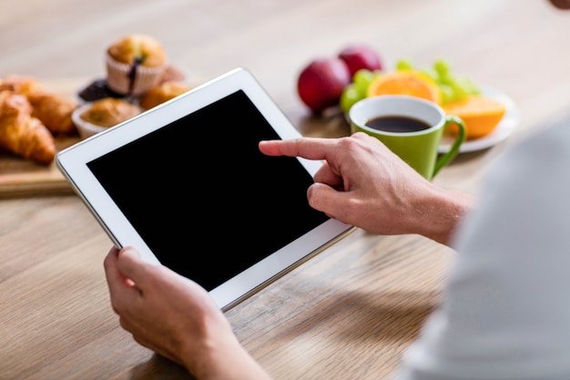 Homem bonito usando tablet na cozinha