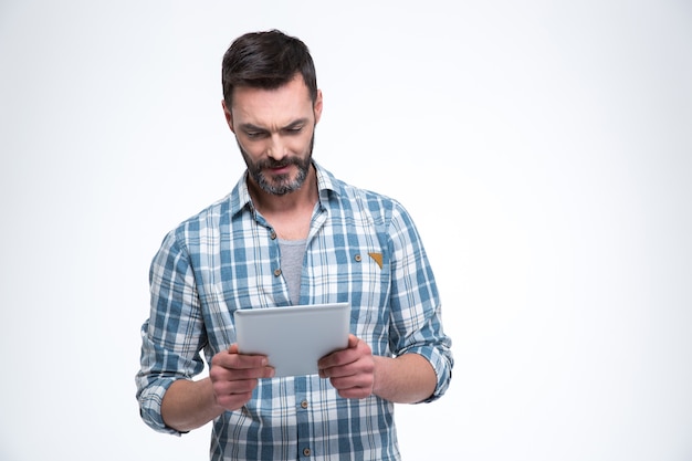 Homem bonito usando um computador tablet isolado em uma parede branca