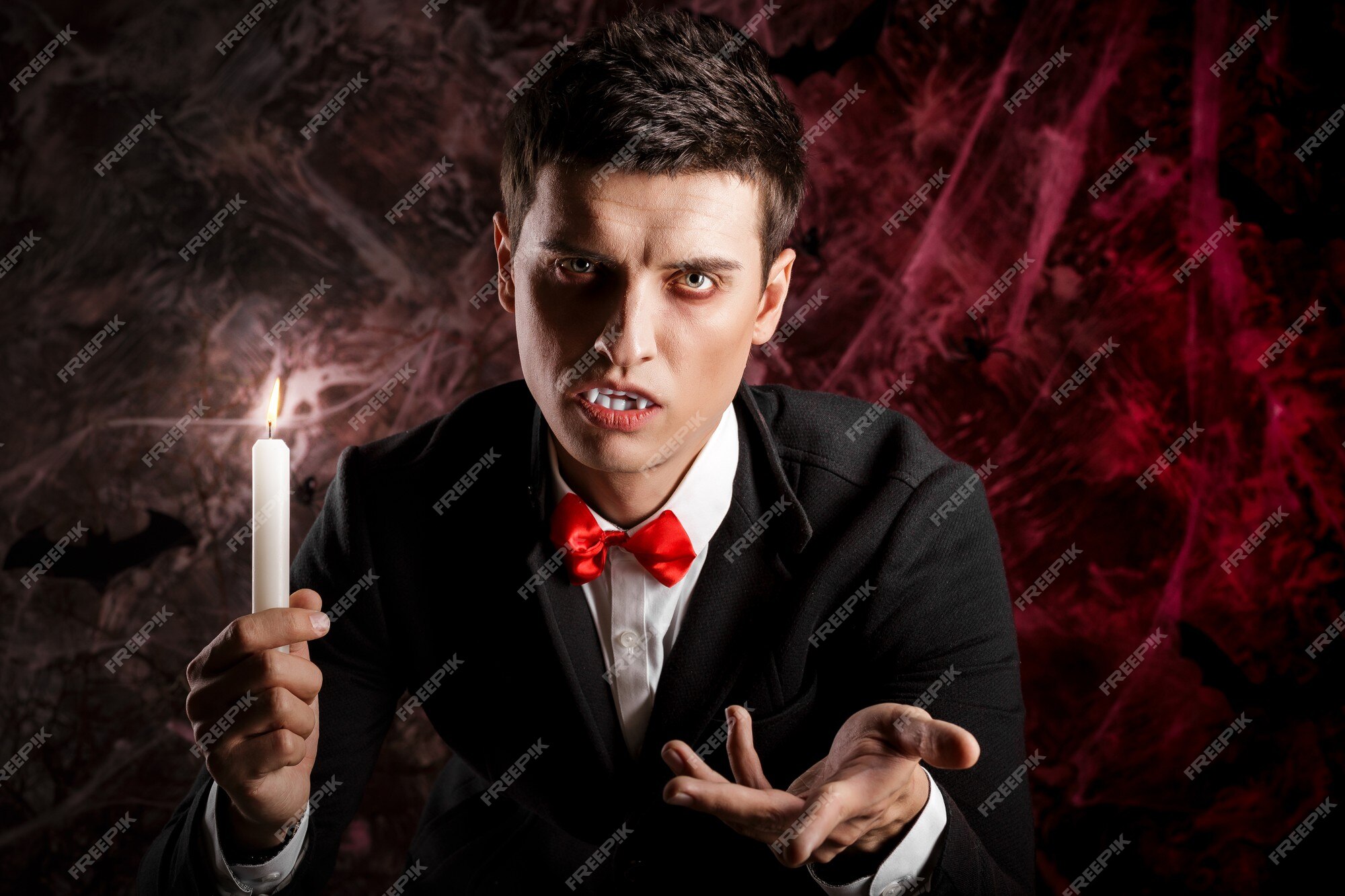 Homem bonito vestido com uma fantasia de drácula para o halloween. vampiro  atraente com velas estende a mão para frente