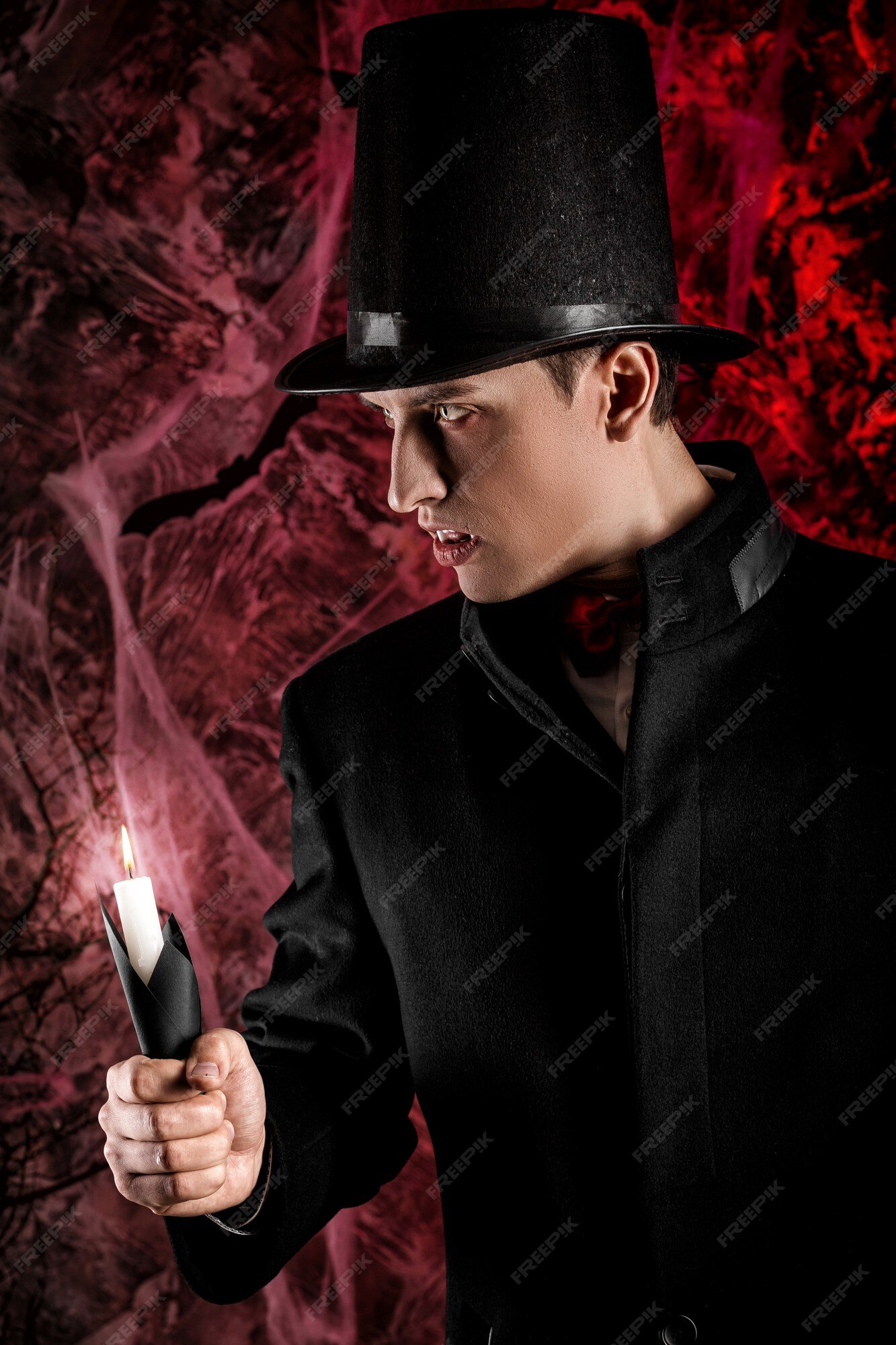 Homem bonito vestido com uma fantasia de drácula para o halloween. vampiro  atraente com velas estende a mão para frente