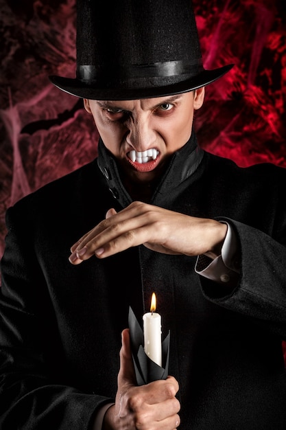 Foto homem bonito vestido com uma fantasia de drácula para o halloween. vampiro horrível com velas