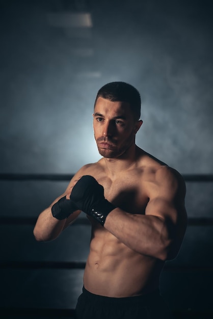 Homem boxer posando em bandagem no conceito de boxe e fitness ringue de boxe