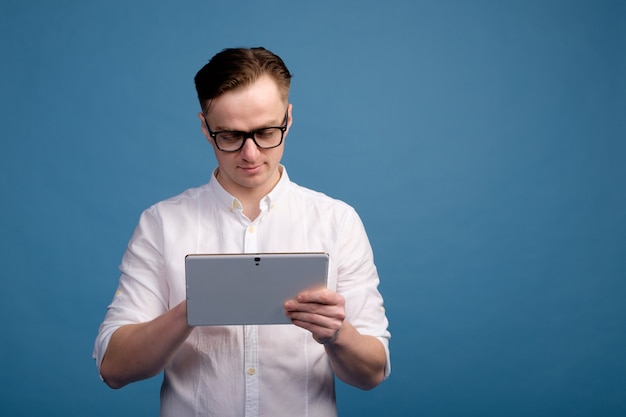 Homem branco bonito em copos vestindo camisa branca usar tablet