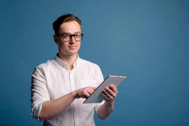 Homem branco bonito em copos vestindo camisa branca usar tablet