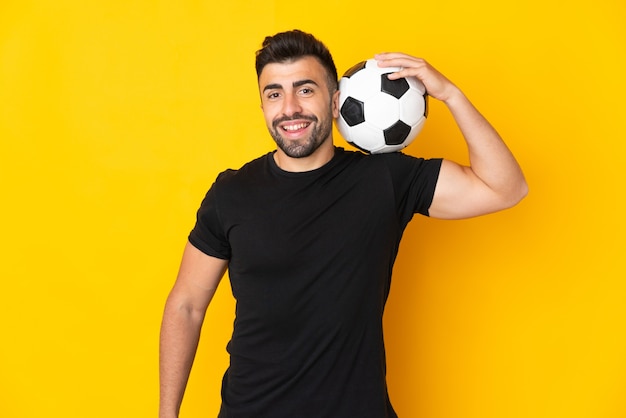 Homem branco isolado amarelo com bola de futebol