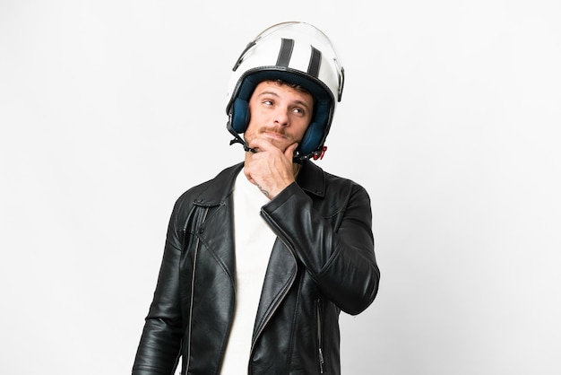 Homem brasileiro com um capacete de moto sobre fundo branco isolado tendo dúvidas