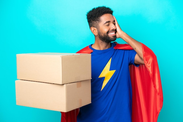 Homem brasileiro de entrega de super-herói isolado em fundo azul sorrindo muito