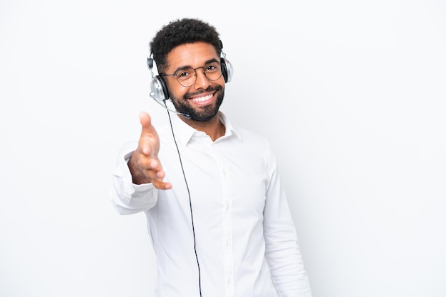 Homem brasileiro de telemarketing trabalhando com um fone de ouvido isolado no fundo branco, apertando as mãos para fechar um bom negócio