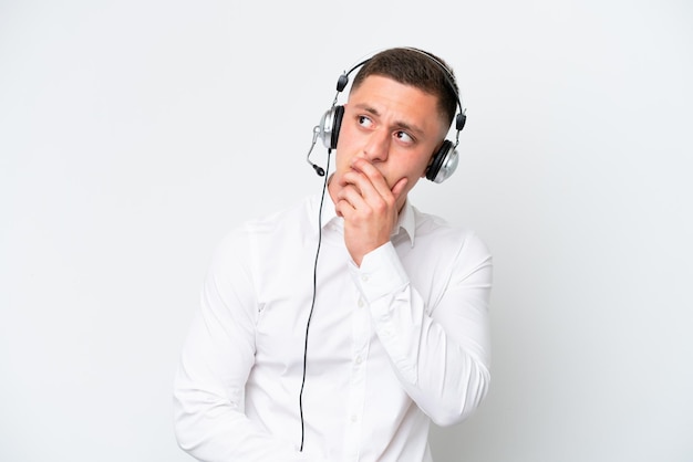 Homem brasileiro de telemarketing trabalhando com um fone de ouvido isolado no fundo branco com dúvidas e com expressão facial confusa