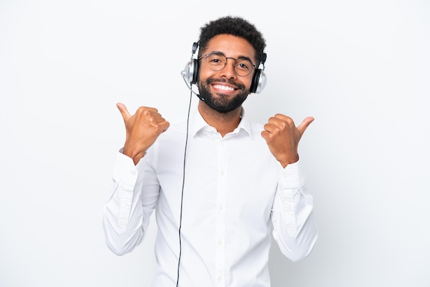 Homem brasileiro de telemarketing trabalhando com um fone de ouvido isolado no fundo branco com polegares para cima gesto e sorrindo