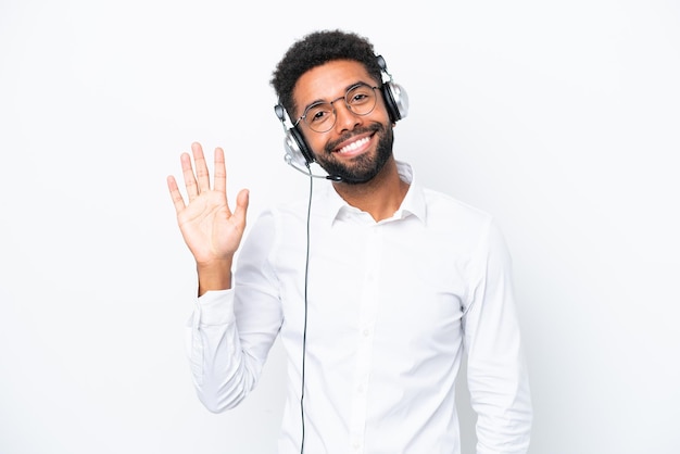 Homem brasileiro de telemarketing trabalhando com um fone de ouvido isolado no fundo branco saudando com a mão com expressão feliz