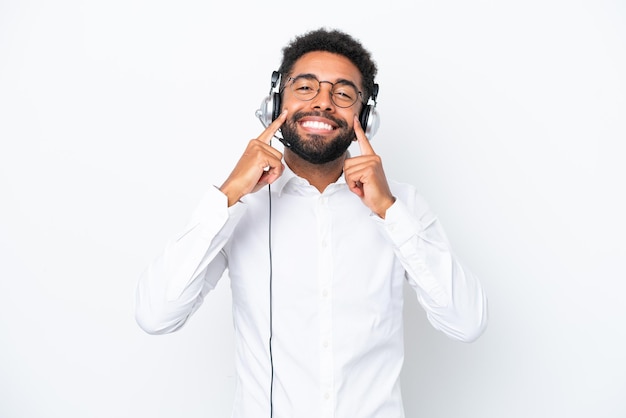 Homem brasileiro de telemarketing trabalhando com um fone de ouvido isolado no fundo branco sorrindo com uma expressão feliz e agradável