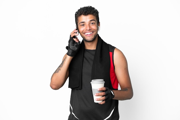 Homem brasileiro do esporte com uma toalha isolada no fundo branco segurando um café para levar e um celular