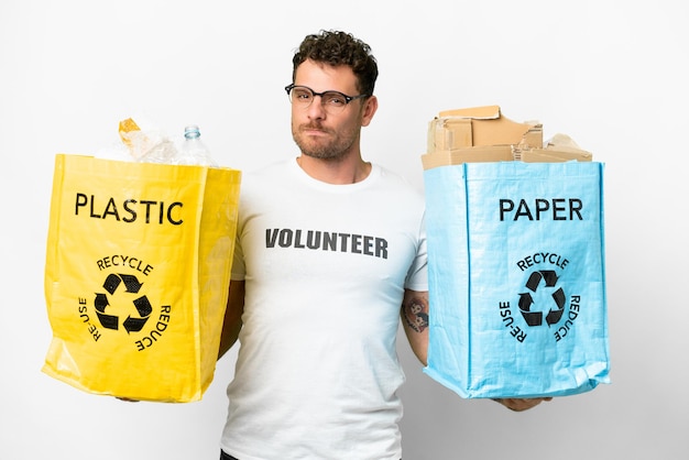 Homem brasileiro segurando saco de reciclagem sobre fundo branco isolado