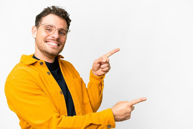 Homem brasileiro sobre fundo branco isolado, apontando o dedo para o lado e apresentando um produto