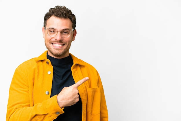 Foto homem brasileiro sobre fundo branco isolado, apontando para o lado para apresentar um produto