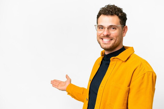 Homem brasileiro sobre fundo branco isolado, estendendo as mãos para o lado para convidar para vir