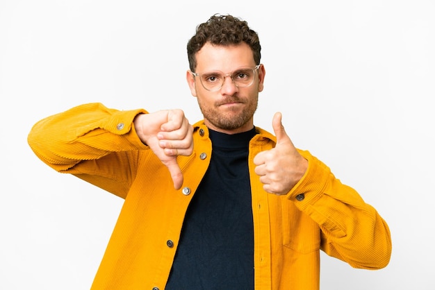 Homem brasileiro sobre fundo branco isolado fazendo sinal bom e ruim Indeciso entre sim ou não