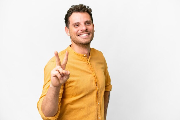 Homem brasileiro sobre fundo branco isolado, sorrindo e mostrando sinal de vitória