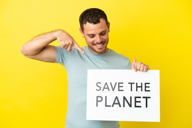 Homem brasileiro sobre fundo roxo isolado segurando um cartaz com o texto Salve o Planeta e apontando-o