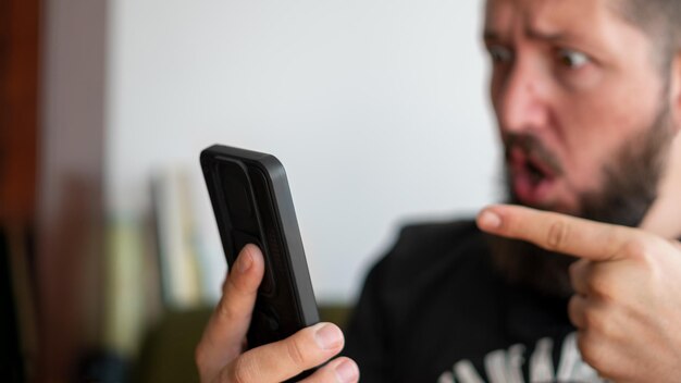 Foto homem bravo gritando e apontando para seu telefone durante uma chamada de vídeo