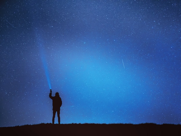 Foto homem brilha lanterna no céu