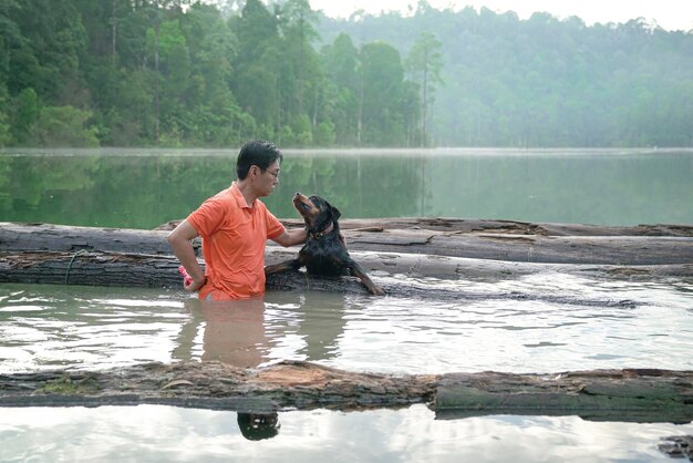 Foto homem brincando com cachorro de estimação no lago