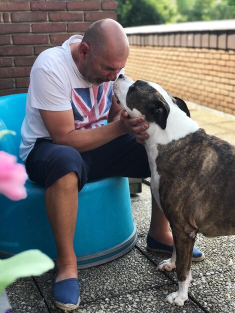 Foto homem brincando com cão na calçada